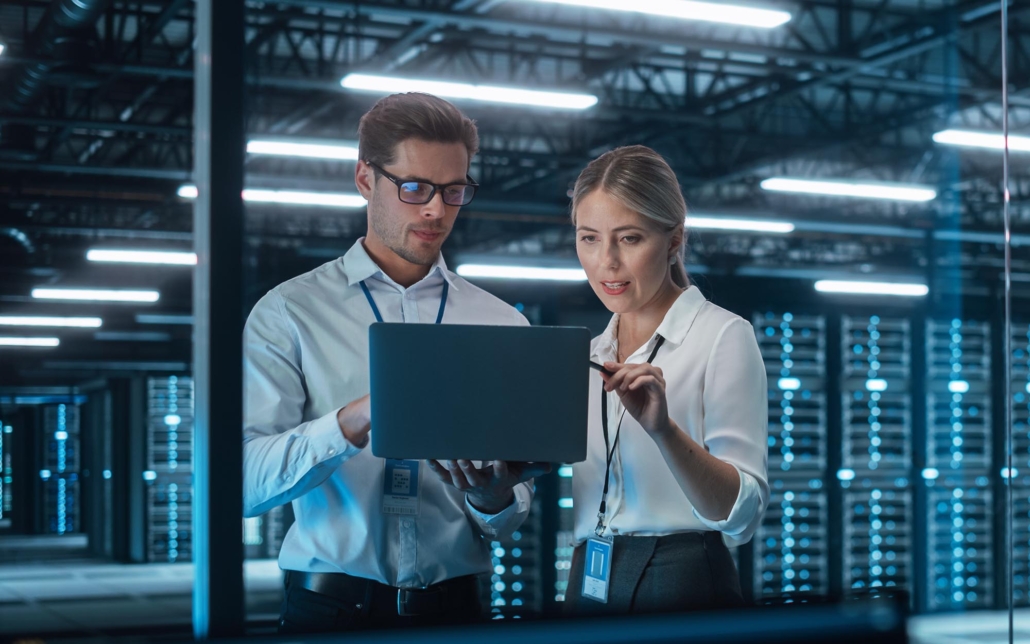 Two people looking at laptop in data center